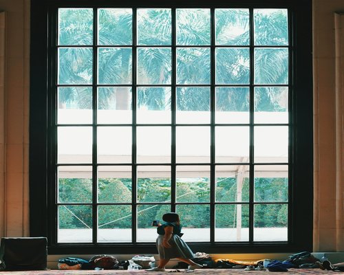 Person enjoying a gentle morning stretch by the window in a Jakarta apartment